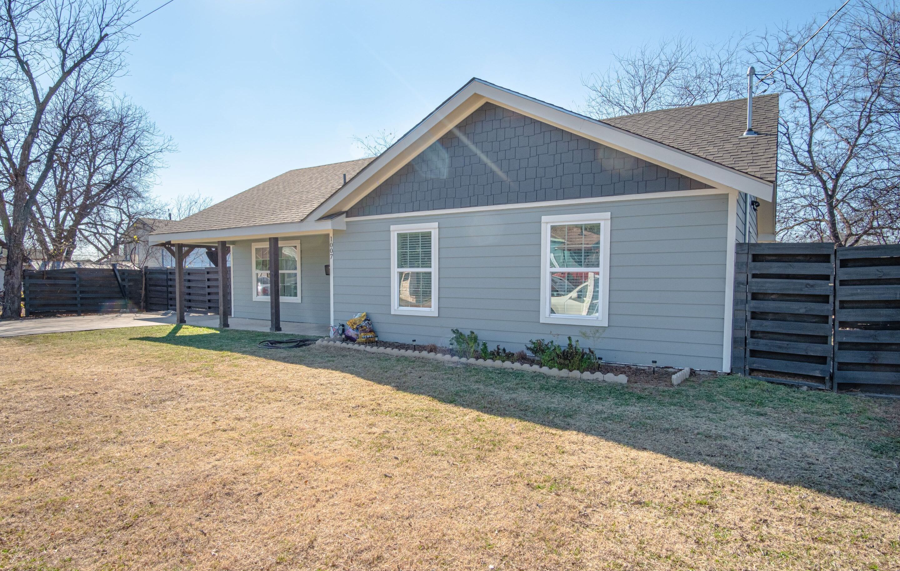 A single-story house with a gabled roof, a covered porch, and a fenced yard.