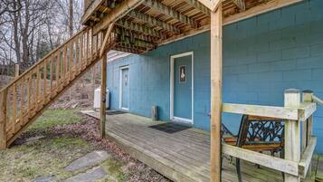 A wooden deck leading to a blue building with a door and windows.