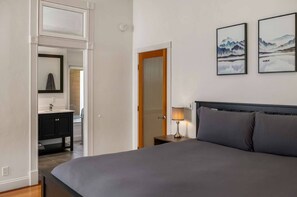 Ein Hotelzimmer mit Bett, Nachttisch, Lampe und zwei gerahmten Bildern an der Wand.