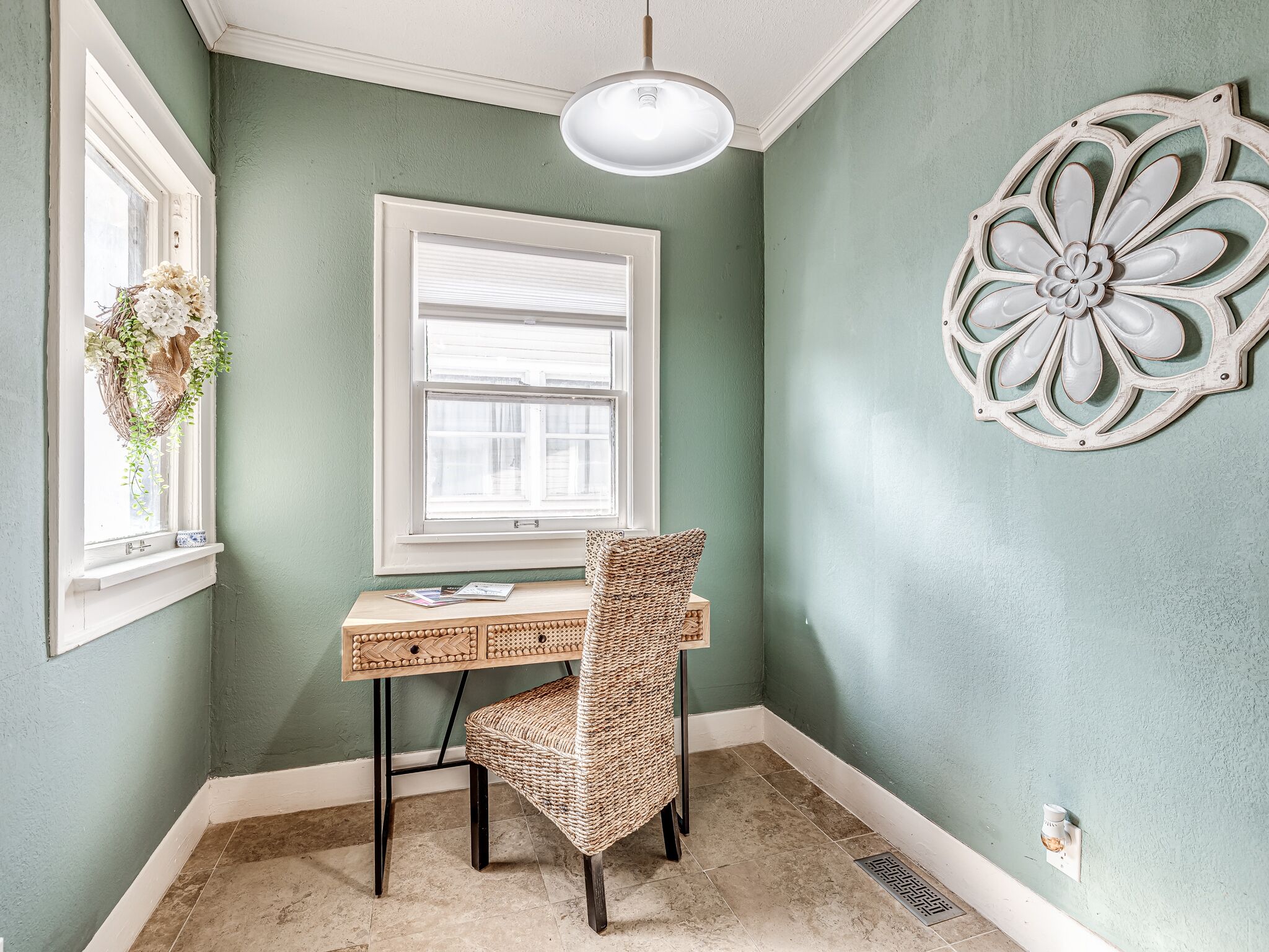 A room with a desk, chair, and decorative wall piece.