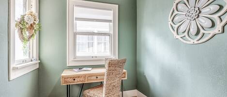 A room with a desk, chair, and decorative wall piece.