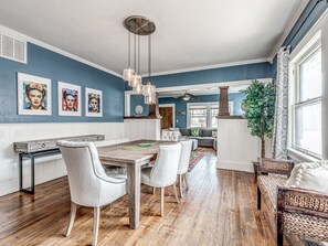 A dining area with a wooden table and chairs, a ceiling fan, and artwork on the walls. - The Frida House in the Urban Core (Oklahoma City)