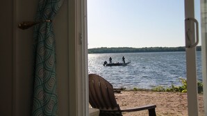 Uitzicht vanuit een kamer op een meer met een boot en mensen.