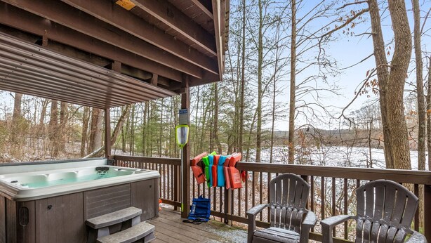 Una terraza de madera con un jacuzzi, sillas y chalecos salvavidas.