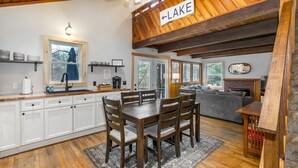 Una cocina moderna con armarios blancos, una mesa de comedor de madera y un letrero que dice 'LAKE'.