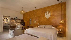 A bedroom with two beds, a sitting area with a chair and table, and a kitchenette. - Wayuum Suites 1: Oasis in Paradise (San Miguel de Cozumel)