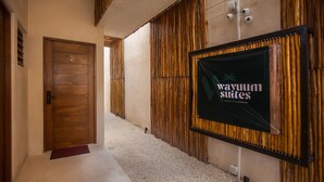 A hallway with a wooden door labeled '2', a bamboo wall, and a sign for 'Wayum Suites Oasis in Paradise'. - Wayuum Suites 1: Oasis in Paradise (San Miguel de Cozumel)