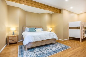 A bedroom with a wooden bed, a nightstand, a lamp, and a bunk bed.