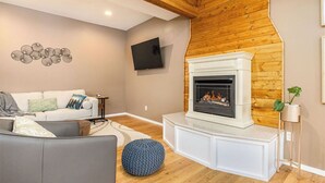 Una sala de estar con chimenea, un sofá, un televisor y un adorno en la pared.