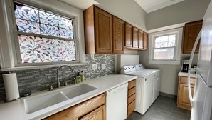A kitchen with wooden cabinets, a white countertop, a dishwasher, a stove, and a refrigerator. - Cozy Double King Suite Bungalow (Great Bend)