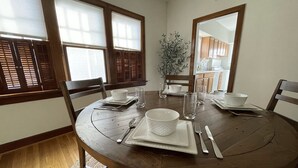 A dining area with a round wooden table, chairs, and a mirror on the wall. - Cozy Double King Suite Bungalow (Great Bend)