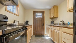 A kitchen with wooden cabinets, a stainless steel refrigerator, and a built-in oven. - The Love Shack (Hocking Hills Area) (Rockbridge)