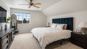 Quarto com cama, ventoinha no teto, janela, cômoda e espelho.