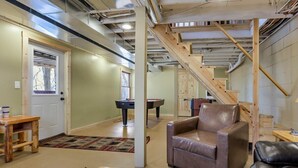 A spacious living area with a wooden staircase, a pool table, and a leather armchair. - Cliff's Edge (Hocking Hills Area) (Amanda)