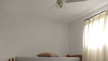 A bunk bed with a ladder, a ceiling fan, and a window with curtains.