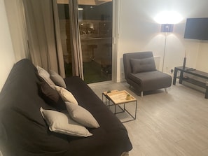 A modern living room with a dark sofa, a grey armchair, and a wooden coffee table. - Pleasant modern studio with swimming pool, 8 minutes from the sea on foot (Antibes)