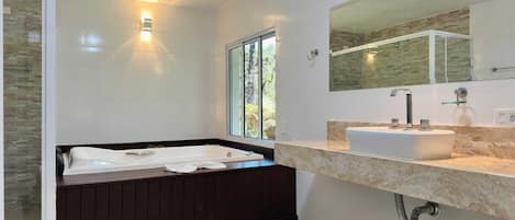 A modern bathroom with a bathtub, a sink, and a large mirror.