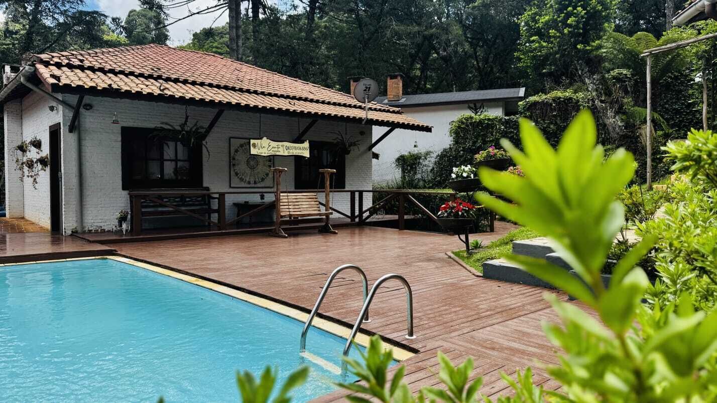 A pool area with a wooden deck, a white building with a tiled roof, and a sign indicating a restaurant.