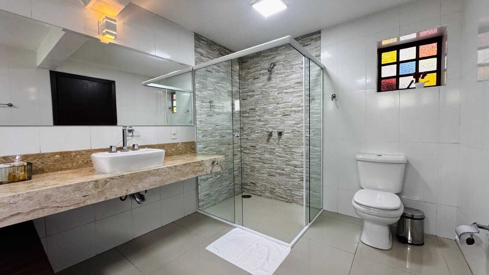 A modern bathroom with a glass-enclosed shower, a white toilet, and a marble countertop.