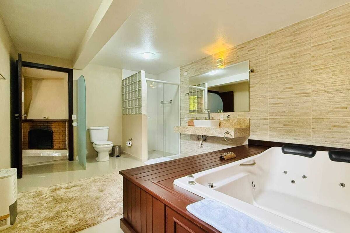 Un baño moderno con una bañera de madera, un cerramiento de ducha de vidrio y un espejo grande.