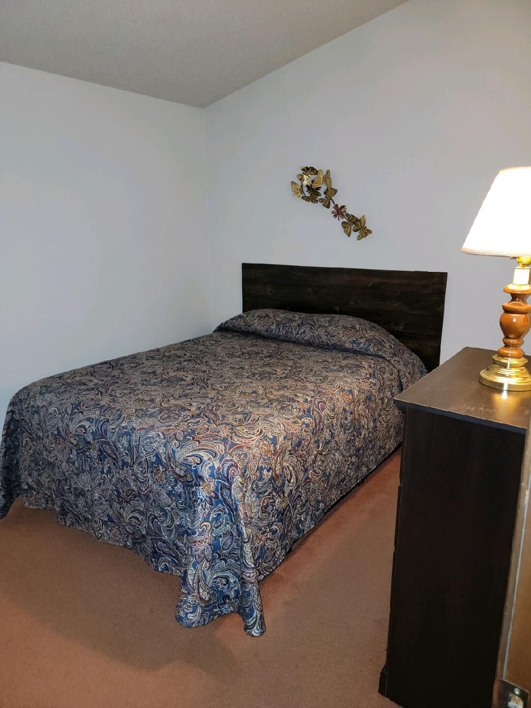 A bedroom with a bed, a nightstand, and a wall-mounted lamp.