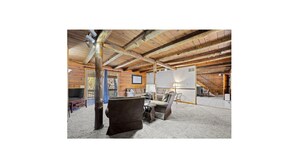 Een ruime loft met zichtbare houten balken, een open haard en een gezellige zithoek.