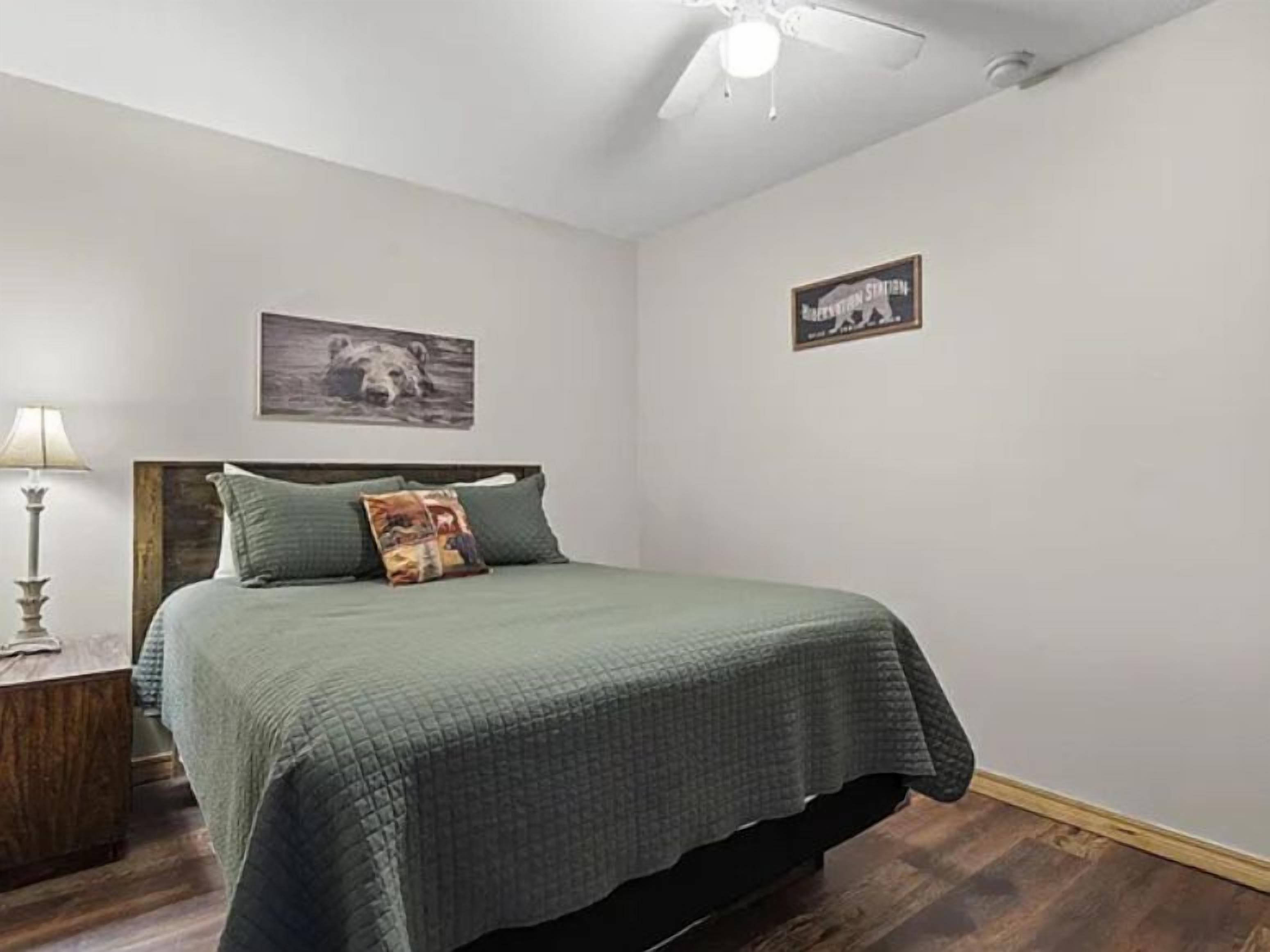 Un dormitorio con una cama, una mesita de noche, una l ámpara y dos cuadros colgados en la pared.