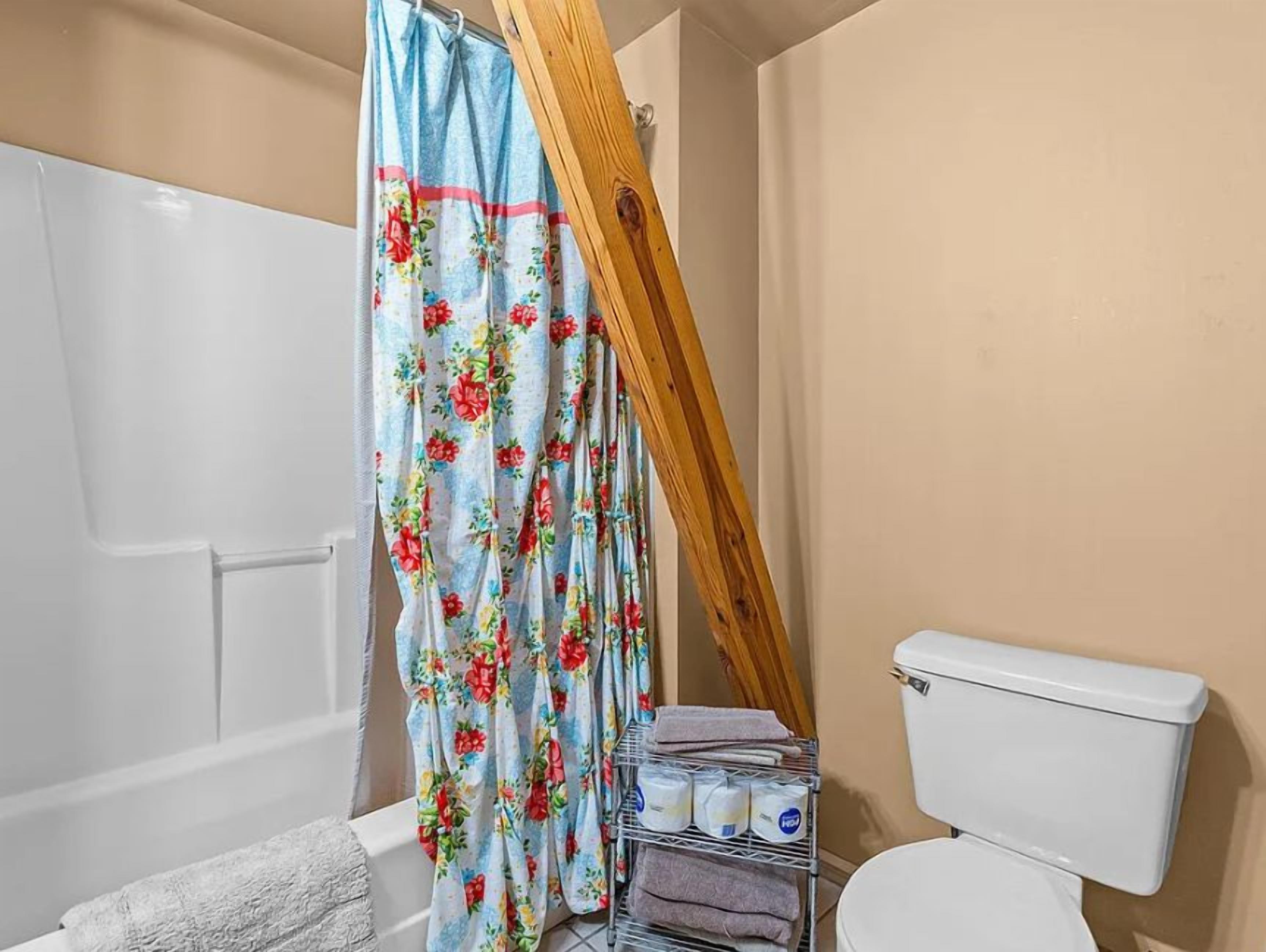 Ein Badezimmer mit Duschvorhang, Toilette und Handtuchhalter.