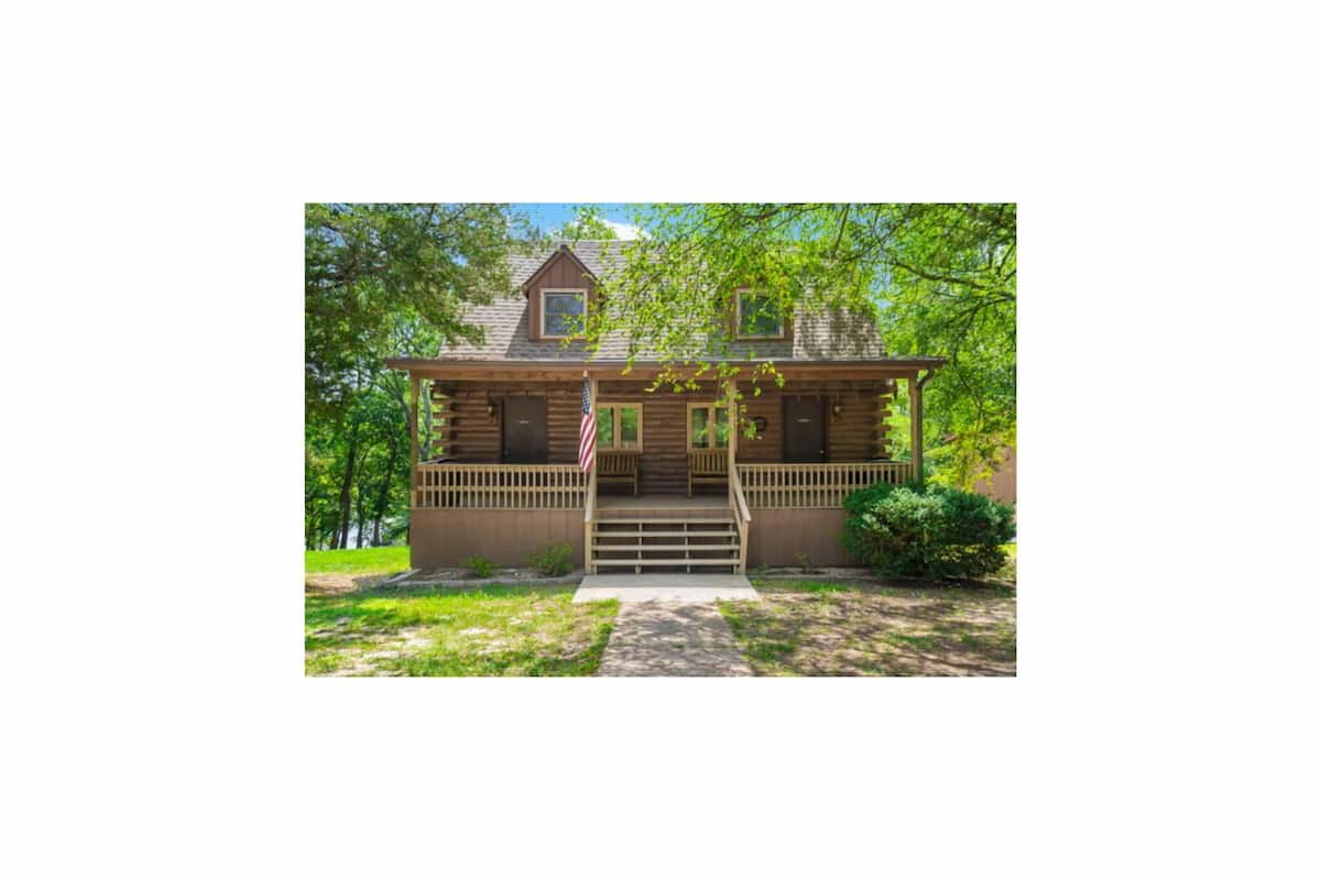 A wooden cabin with a porch, steps, and an American flag.