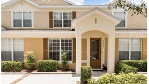 A two-story building with a symmetrical facade, large windows, and a central entrance with a small porch. - Three BR * 2 Miles to Disney, pool, free WiFi and more (Kissimmee)