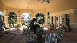 A covered outdoor area with tiled flooring, striped chairs, and ceiling fans. - Three BR * 2 Miles to Disney, pool, free WiFi and more (Kissimmee)