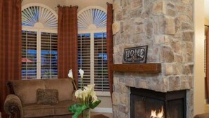 A living room with a stone fireplace, a ceiling fan, and a sofa. - Waterfront, LuxuryVilla with Private Pool- (Chandler)