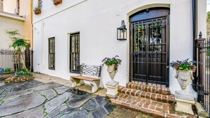 A white building with a black door, two windows, a bench, and potted plants. - Downtown+FREE Parking+Walk Everywhere+Forsyth Park (Savannah)
