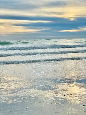 A beach with waves and a cloudy sky.