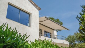 Un bâtiment moderne doté de grandes fenêtres, d’un balcon et offrant une vue sur un ciel dégagé.
