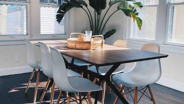 A dining area with a dark wooden table, white chairs, and a plant. - Chic Bungalow Located In The Heart Of Wichita (Wichita)