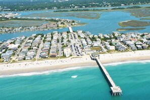 An aerial view of a coastal residential area with a pier extending into the water, surrounded by houses and a beach. - Luxe Private Beach Getaway Minutes to the Ocean! (Wilmington)