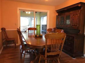 A dining room with a wooden table and chairs, a green vase, and a wooden cabinet.