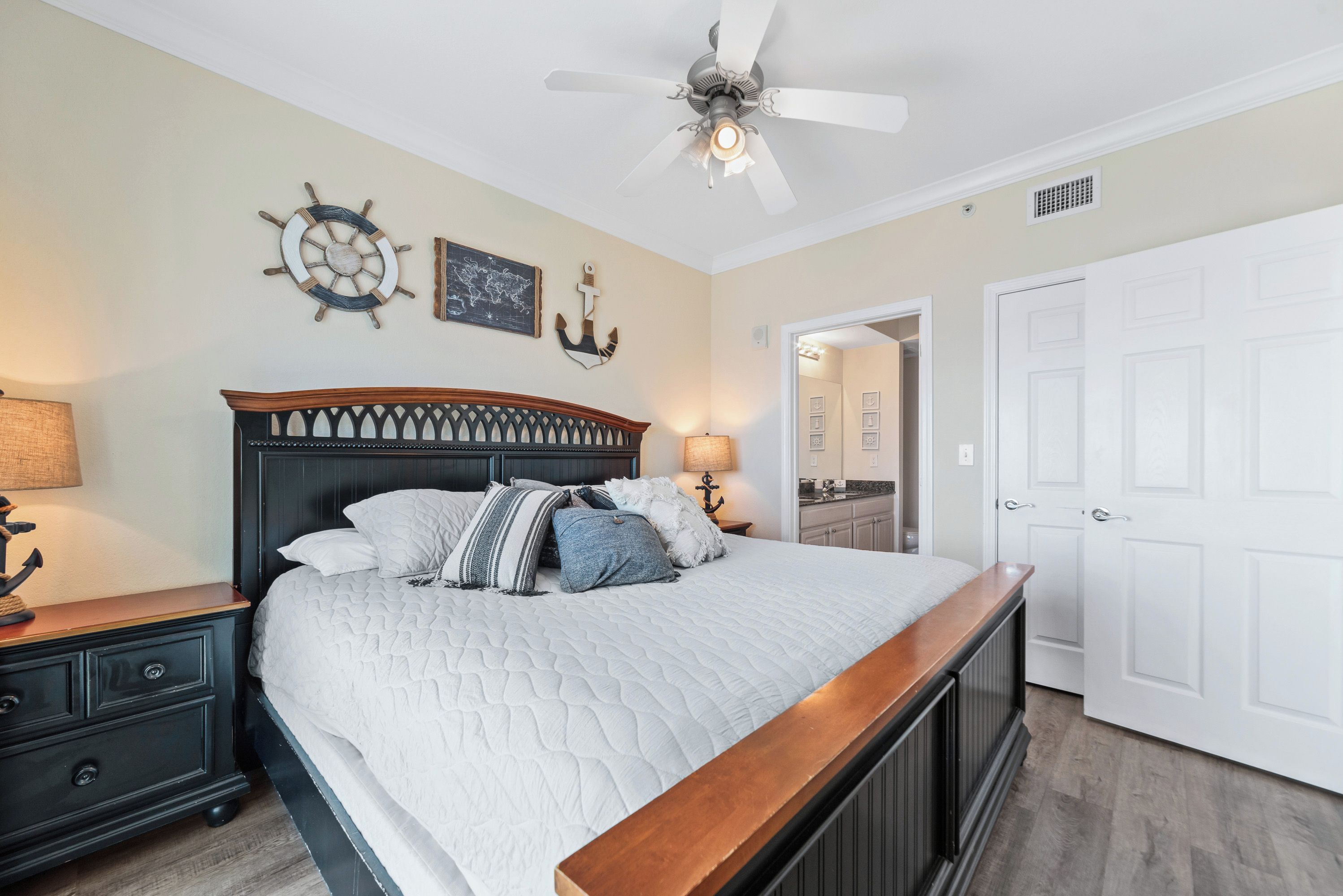 A bedroom with a bed, nightstands, a ceiling fan, and a door.
