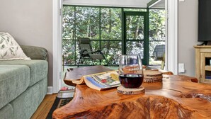 A cozy living area with a wooden coffee table, a glass of red wine, a book, and a green sofa.