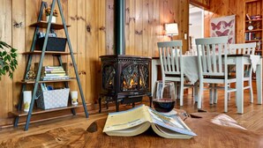 A cozy room with a wooden interior, a bookshelf, a table with chairs, and a fireplace.