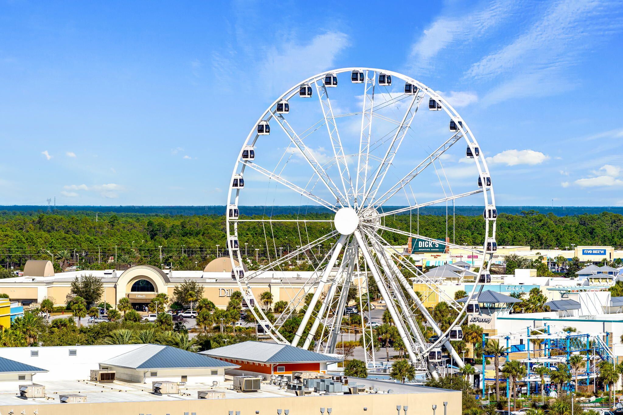 A large Ferris wheel with gondolas, surrounded by commercial buildings and a clear sky.