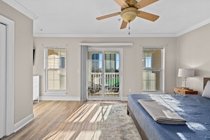 A bedroom with a bed, a ceiling fan, a window, and a view of the outside.