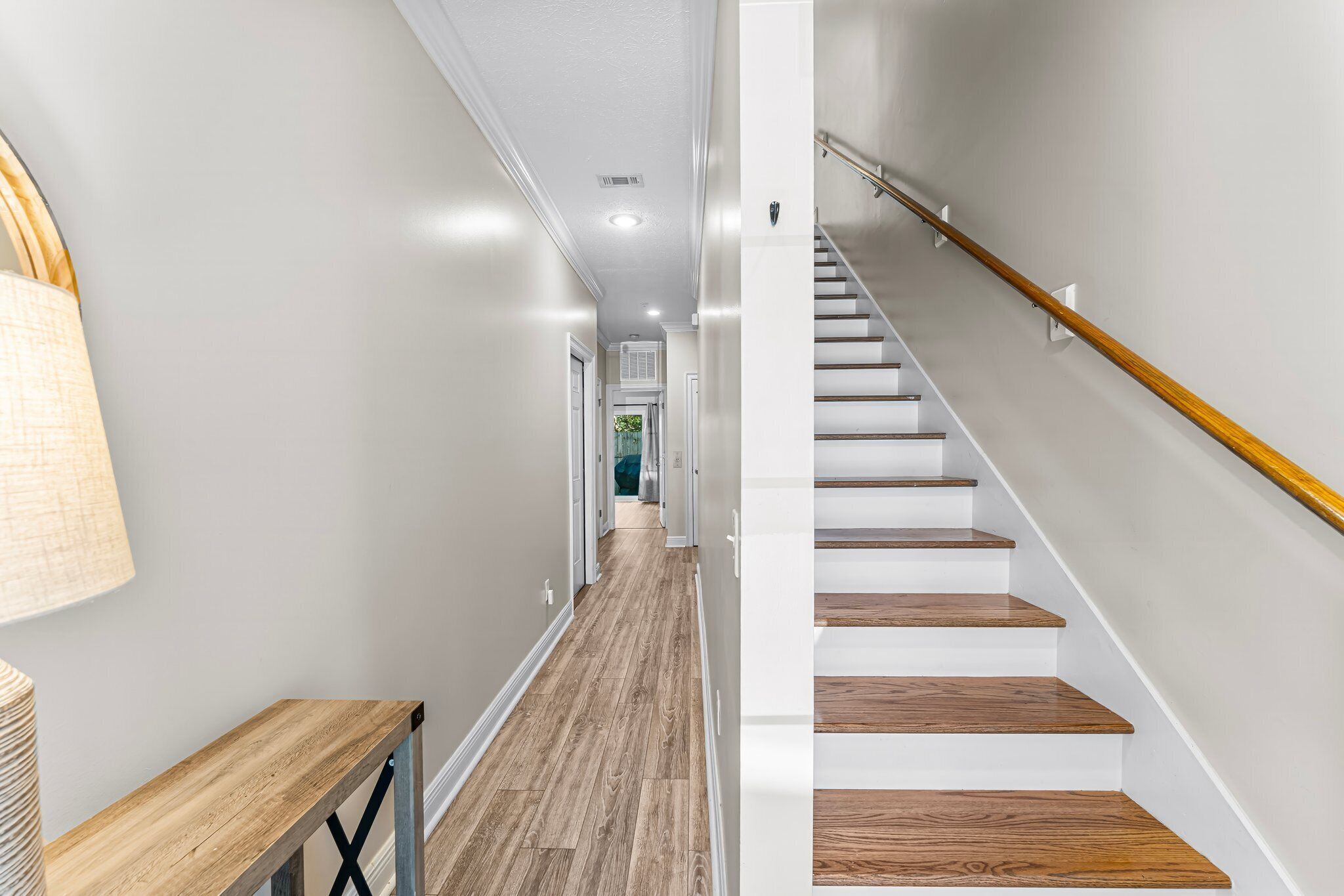 A modern interior with a wooden floor, white walls, and a staircase with a wooden handrail.