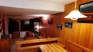 A cozy room with wooden walls and a bench. There are framed pictures on the wall and a lamp hanging above the bench. - Apartment La Tania Courchevel 4 to 6 people<br> at the foot of the slopes,  (La Tania, Courchevel)