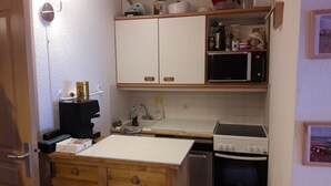 A compact kitchen with white cabinets, a microwave, a stove, and a sink. - Apartment La Tania Courchevel 4 to 6 people<br> at the foot of the slopes,  (La Tania, Courchevel)