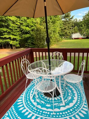 A patio with a round table and white chairs, a beige umbrella, and a blue patterned rug. - Serenity near Lake Gaston 3BR 4 Work &Play Cozy & Spacious 15 mins to South Hill (Bracey)