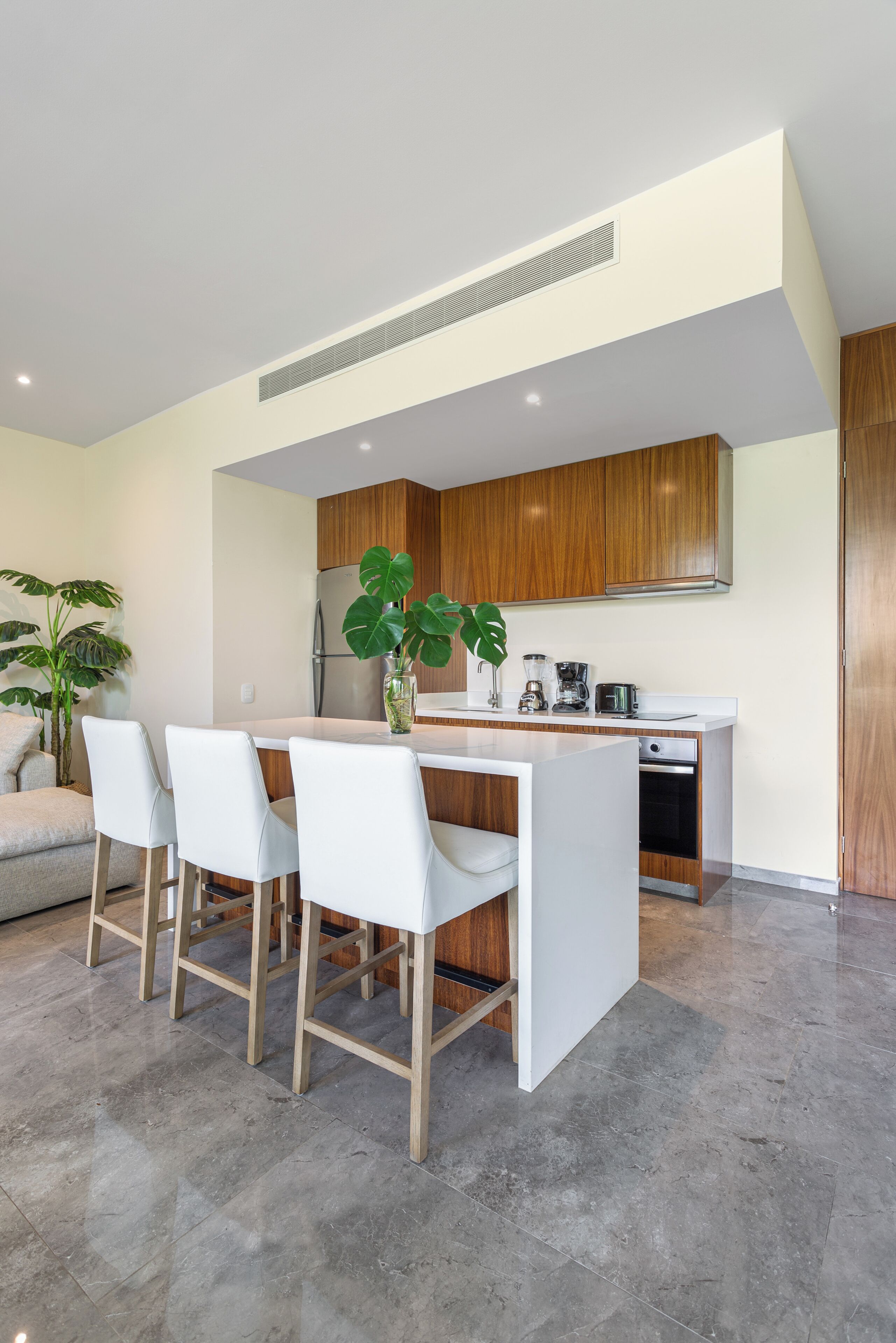 Une cuisine moderne avec des meubles blancs, un îlot central et un coin repas avec des chaises blanches.