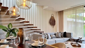 A modern dining area with a wooden table set for a meal, a sofa, and a staircase with wooden steps. - Mistiq Tulum (Tulum)