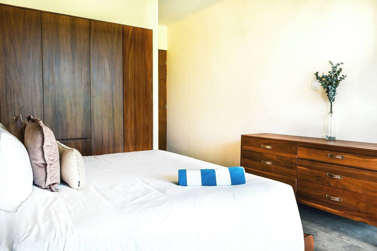 A bedroom with a bed, wooden wardrobe, and a dresser.